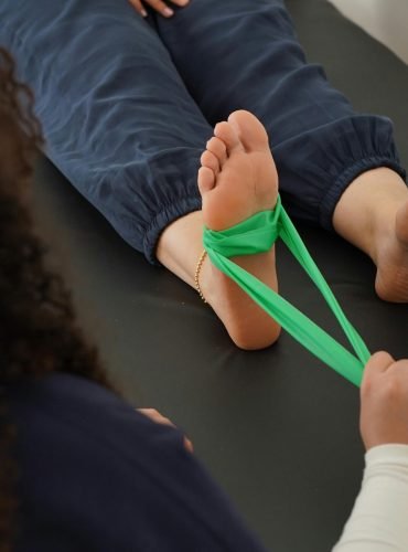 Close-up of a physical therapy session using a resistance band for foot rehabilitation.